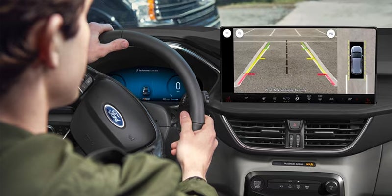Driver looking at the car's backup camera display on the central screen