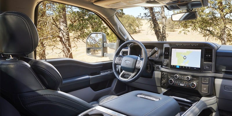 Truck interior showing black leather seats, steering wheel, and a navigation screen